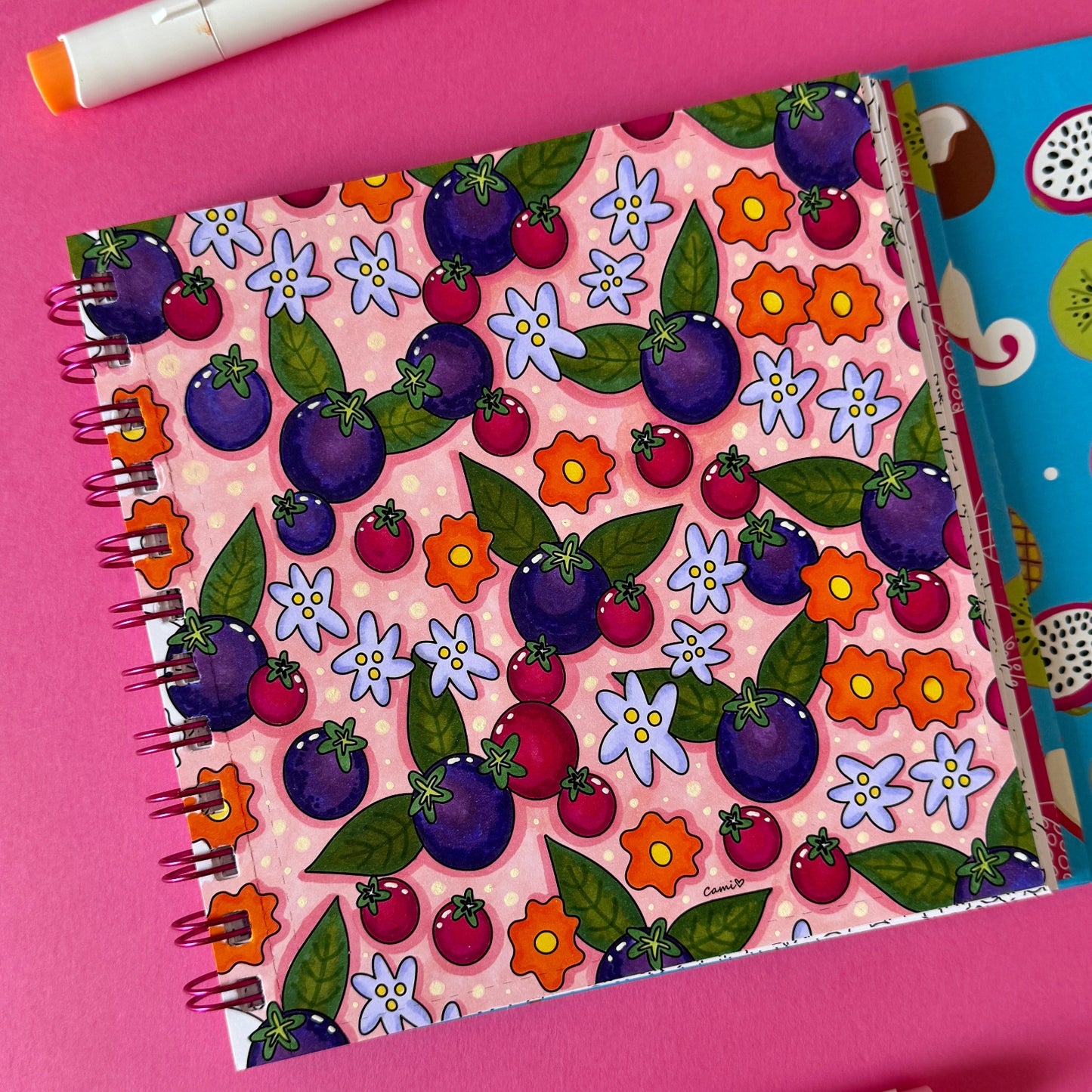 Libro para colorear FRUTALIA con coloridos patrones de frutas y flores sobre fondo rosado.