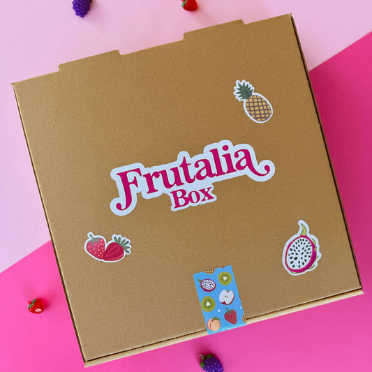 Frutalia Box - caja experiencia con diseño colorido y stickers de frutas en fondo rosa y dorado.